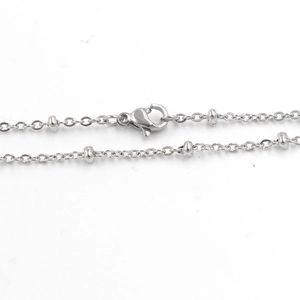 Detailed close-up of a silver stainless steel ball chain necklace with a lobster clasp