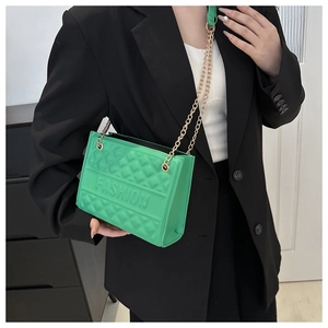 Detail of green quilted handbag with gold chain strap and embossed fashion logo