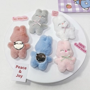Ensemble de cinq broches lapin en peluche colorées blanc, rose et bleu sur plateau