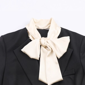 Black blazer featuring contrast off-white satin oversized bow collar detail on white background