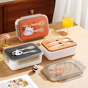 Close-up of divided bento box with cartoon animal graphics and wooden utensils