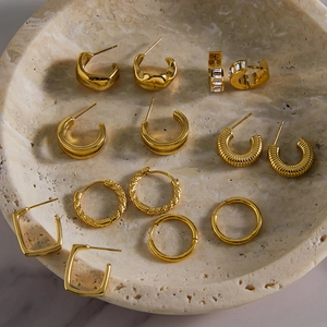 Détail de six paires de boucles d'oreilles dorées en acier titane avec cristaux