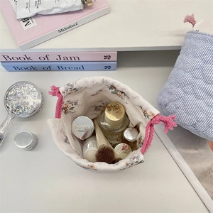 Close-up of floral drawstring storage bag holding perfume, cream and makeup brushes