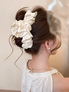 Détail d'un chouchou plissé couleur crème porté sur une coiffure élégante relevée