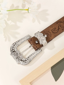Dettaglio fibbia a farfalla argentata con strass su cintura in pelle marrone goffrata