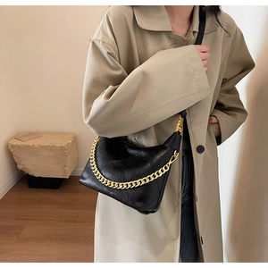 Detail of black quilted leather shoulder bag with thick gold chain and chic texture