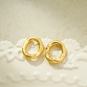 Macro shot of 18K gold earrings with balloon wrinkle texture on a white plate