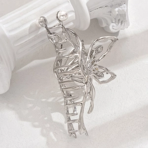 Elegant silver butterfly metal hair claw clip with white pearl accents on white marble
