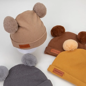 Warm baby knit hats with dual pom-poms and handmade leather tags in four assorted colors