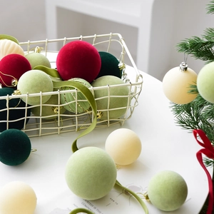 Flocked Christmas ball set in red and green displayed in a basket for tree decoration