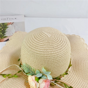 Detail of scalloped edge straw sun hat with pink flowers and a weave rope decor