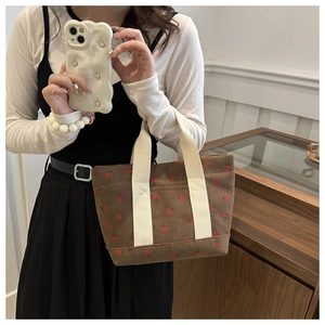 Close-up of brown corduroy tote bag with red strawberry pattern and fabric handles