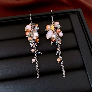 Detailed close-up of crystal beads and leaf charms on silver tassel earrings