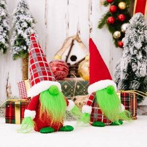 Christmas gnome ornaments with green faux fur beards and festive red hats on white wood