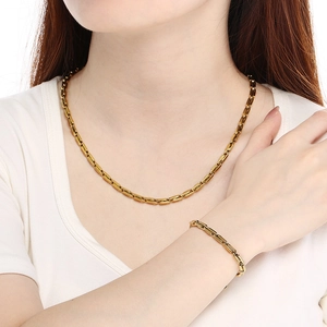 Ensemble collier et bracelet en acier inoxydable doré porté par un mannequin de mode