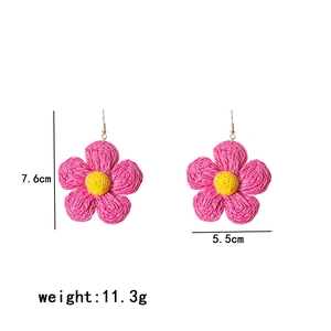 Detailed view of handmade woven raffia flower earrings in pink and yellow with dimensions