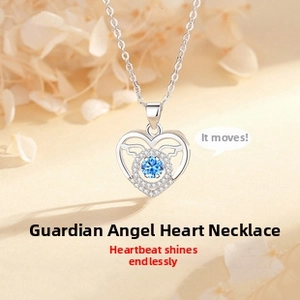 Macro shot of heart-shaped silver necklace with blue center stone and wing detail