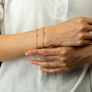 Elegant gold and silver link bracelets with round zircon pendant on a female wrist