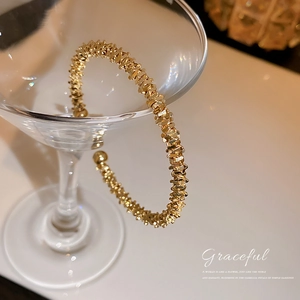 Minimalist adjustable gold open cuff bracelet with elegant textured finish on glass
