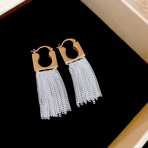 Macro shot of 14k gold-plated square hoops with silver tassel chains in a jewelry box
