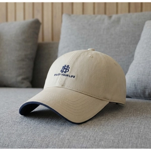 Detailed close-up of beige cotton baseball cap with navy blue slogan embroidery