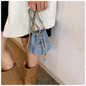 Close-up of denim bucket bag showing quilted texture and golden chain strap detail
