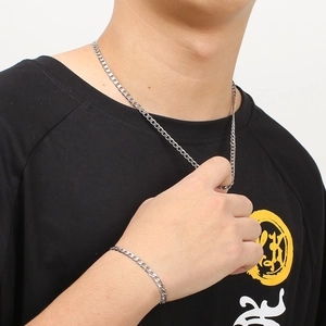 Detail shot of silver stainless steel curb chain necklace and bracelet set on a male model