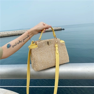 Detail of hand-woven beige straw bag with yellow leather trim and gold metal buckle