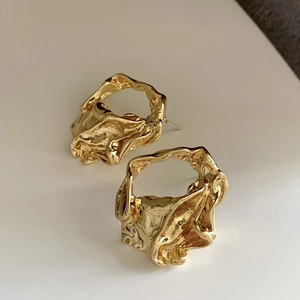 Irregular hollow golden stud earrings with a minimalist lava texture on white background