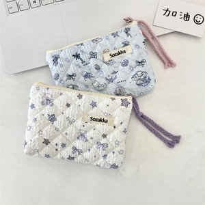 Close-up of quilted floral cosmetic bags with mermaid and bear patterns and cord zippers