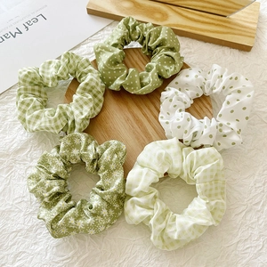 Close-up of five floral and plaid pattern hair scrunchies on a round wooden tray