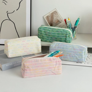 Close-up of knit pencil cases in pastel pink, blue, and green on an aesthetic desk set