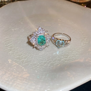 Macro detail of luxury double-layer open rings with emerald and heart-shaped zircon stones