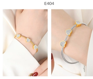Macro detail of gold and silver heart snake chain bracelets with pavé-set crystals