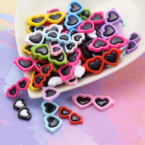 Colorful heart-shaped resin sunglasses miniatures scattered from a white heart bowl