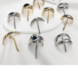 Detailed view of metal hair hooks in gold and silver with hammered texture on white fabric