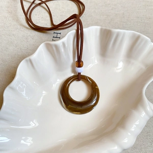 Detailed macro view of the brown marble resin circle pendant with white accent beads