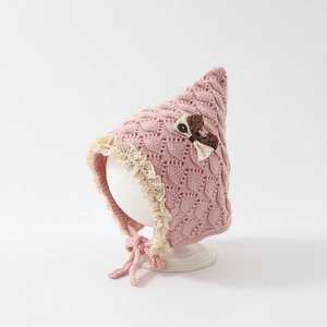 Detail of pink knitted baby hat featuring delicate lace trim and a contrast bow accent