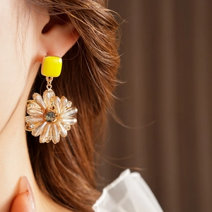 Detailaufnahme luxuriöser gelber quadratischer Blumenohrringe mit Kristallen am Model