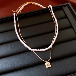 Dettaglio della collana a doppio strato placcata oro 14K con perle e ciondolo Good Luck