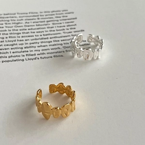 Close-up of irregular wave-textured silver and gold open rings on an aesthetic book background