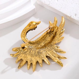 Back view of gold swan brooch showing safety pin clasp and brushed metal texture