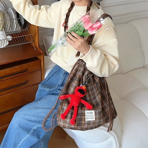 Detailed view of brown plaid drawstring bag with cute red plush doll charm pendant