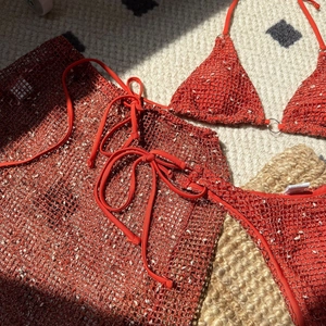 Detail showing orange crochet three-piece bikini set with knit hollow mesh texture