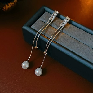 Macro view of long silver tassel earrings with zircon stones and spherical pearls