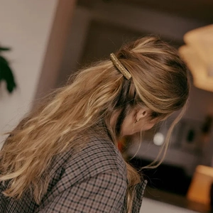Close-up of golden hammered metal hair clip styled on wavy brown hair for a chic look