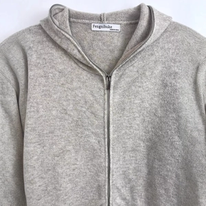 Women's minimalist grey zip-up hooded knit sweater with soft wool texture in a flat lay view