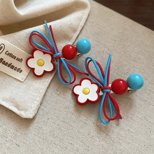 Detail view of handmade bow hair clips with white flower and colorful beads on cotton fabric
