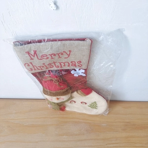 Close-up of a burlap Christmas stocking with snowman design in its plastic packaging