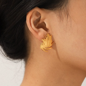 Detailed view of vintage gold-plated braided spiral stud earring on a person's ear